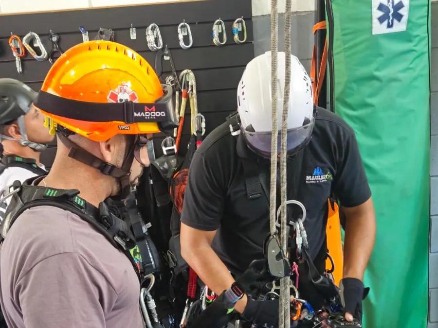 Instrutor ajudando um aluno a ajustar o equipamento de cordas durante um treino prático