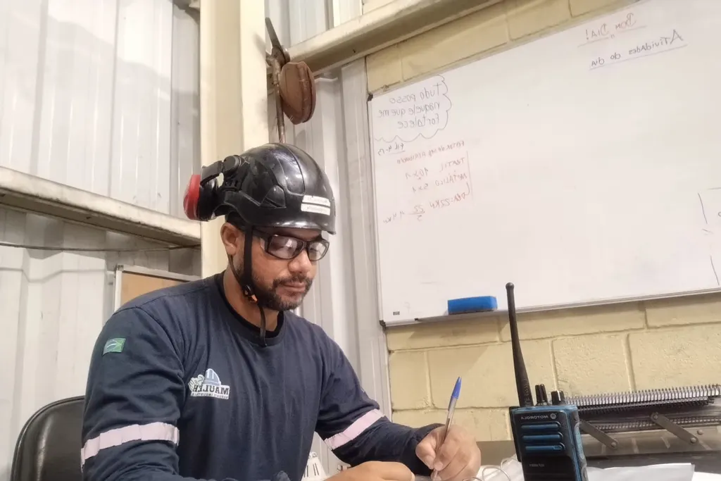 Consultor de capacete e óculos de proteção preenchendo documentos em uma mesa de escritório